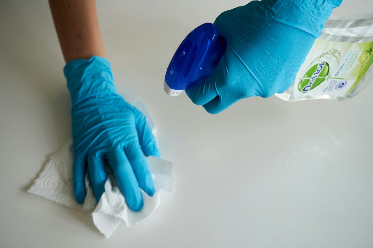 Gloved hand disinfecting a surface